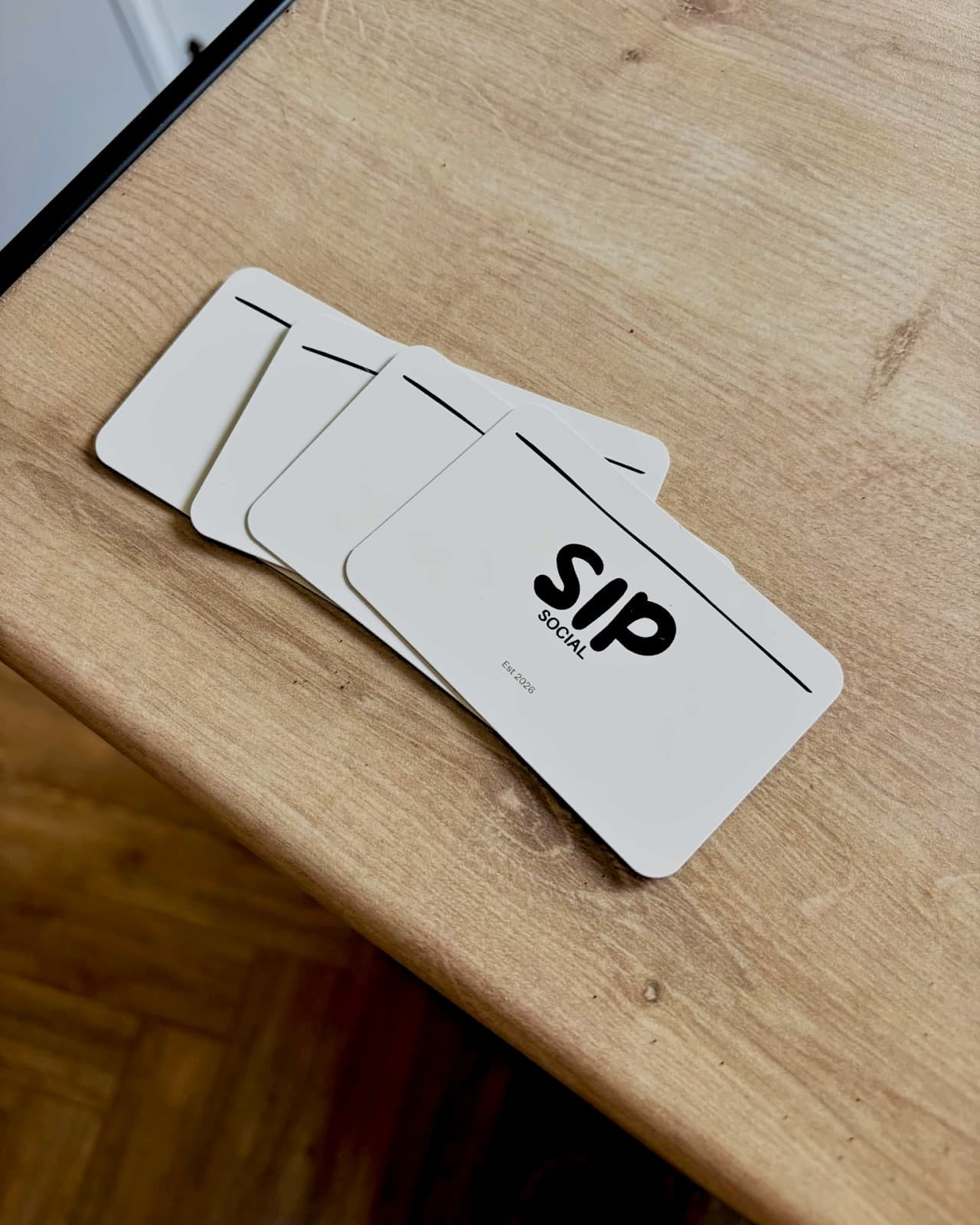 Sip Social business cards fanned out on a wooden table