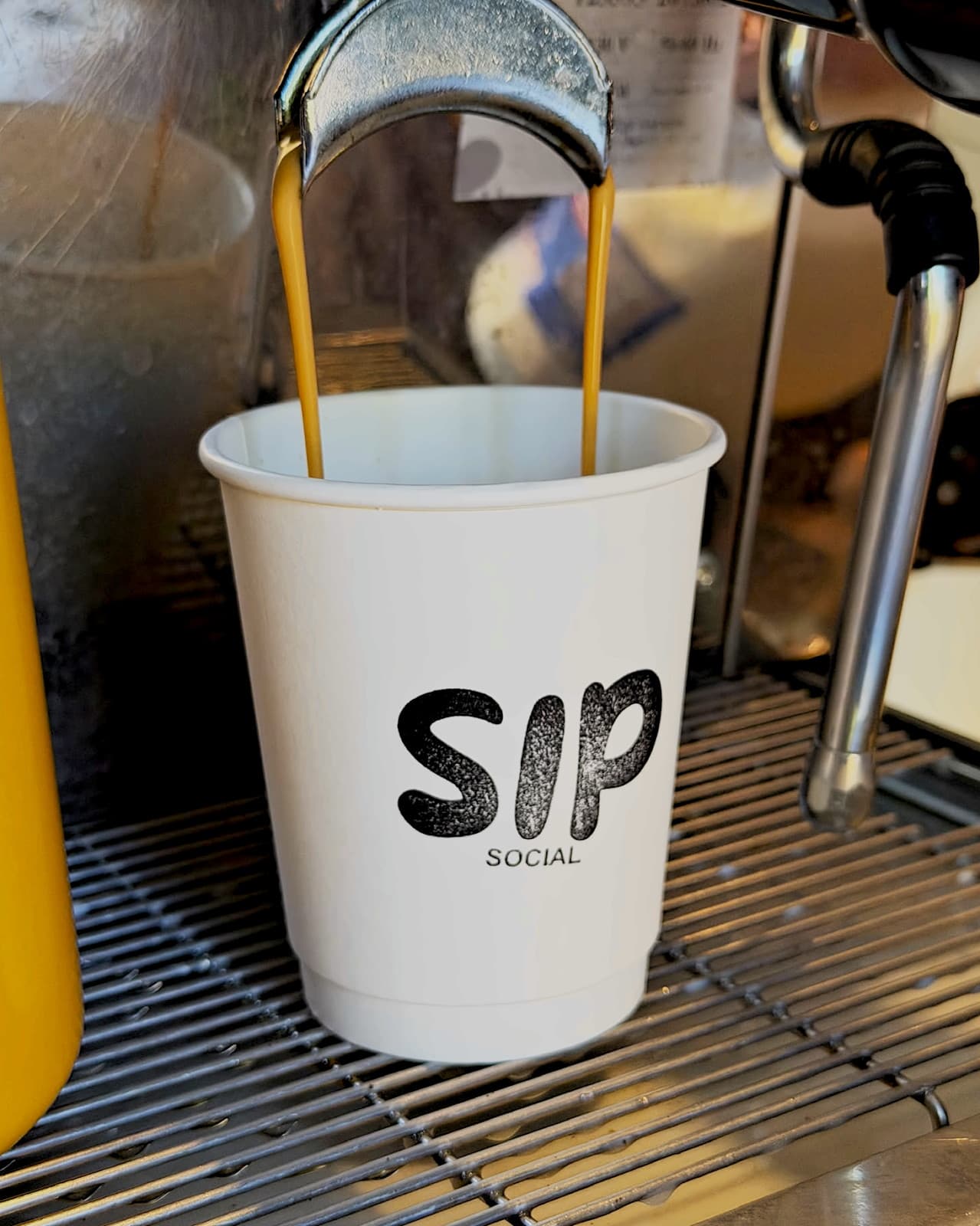Espresso pouring into a branded Sip Social takeaway cup